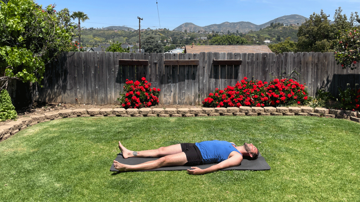 Man lying on a yoga mat in his backyard