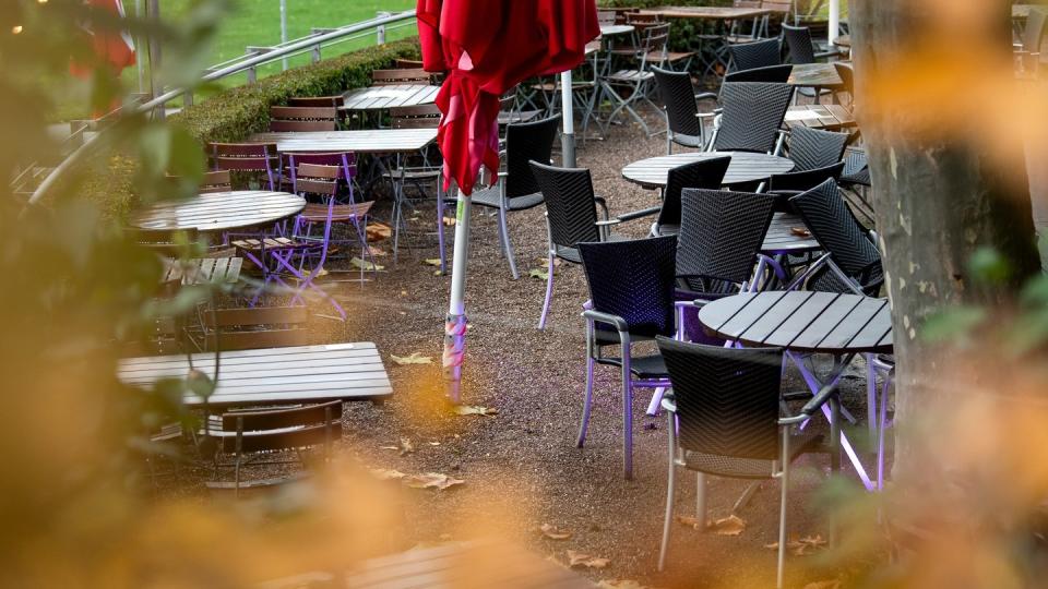 Leere Tische und Stühle stehen vor einem Restaurant.