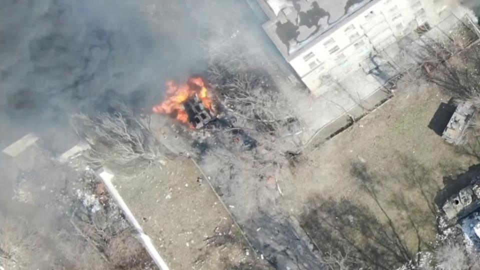 An aerial view shows an armoured vehicle on fire next to a building in Mariupol (via REUTERS)