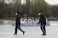 People wearing face masks as a precaution against the coronavirus walk past the display of South Korea's capital Seoul logo at a park in Seoul, South Korea, Tuesday, Nov. 24, 2020. Authorities in the South Korean capital on Monday announced a tightening of social distancing regulations, including shutting nightclubs, limiting service hours at restaurants and reducing public transportation. (AP Photo/Lee Jin-man)