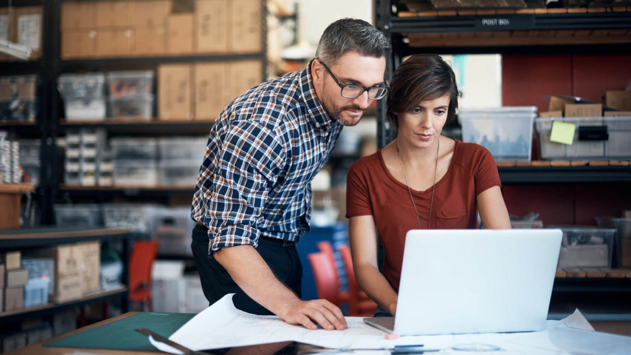 Shot of a man and woman using a laptop while working on a project together in a workshop.