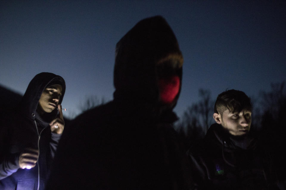 In this picture taken Saturday Dec. 14, 2019, Afghan migrants stand near an abandoned farm located in the Bosnian side of the mountains near the border with Croatia as they wait to make another attempt to cross into the EU near Bihac, northwestern Bosnia.(AP Photo/Manu Brabo)