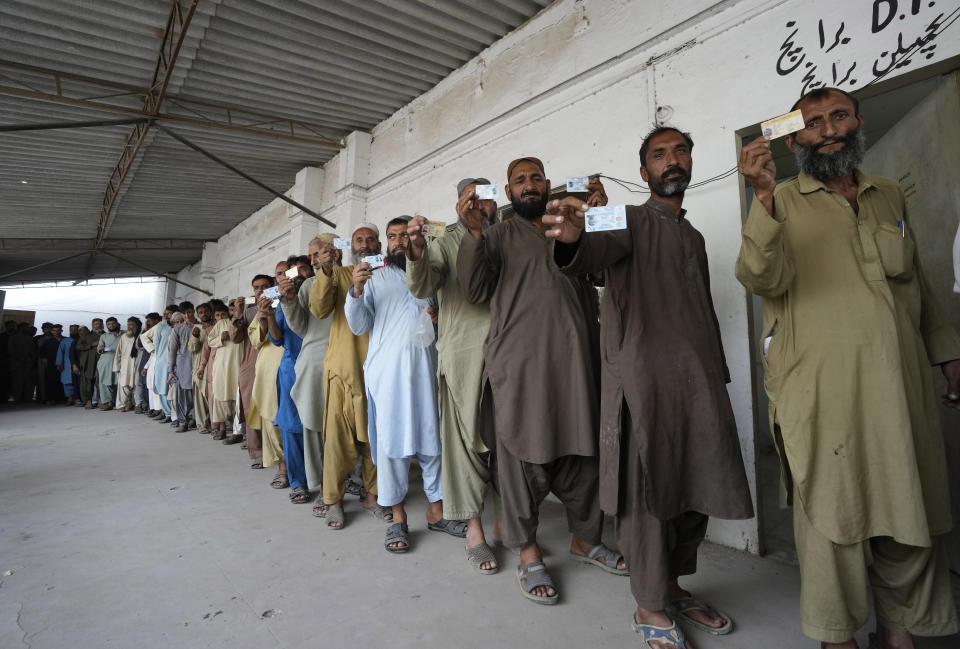 Immigrants, mostly Afghans, show their ID cards as they wait their turn to verify data at a counter of Pakistan's National Database and Registration Authority, in Karachi, Pakistan, Tuesday, Nov. 7, 2023. Pakistan government launched a crackdown on migrants living in the country illegally as a part of the new measure which mainly target all undocumented or unregistered foreigners. (AP Photo/Fareed Khan)