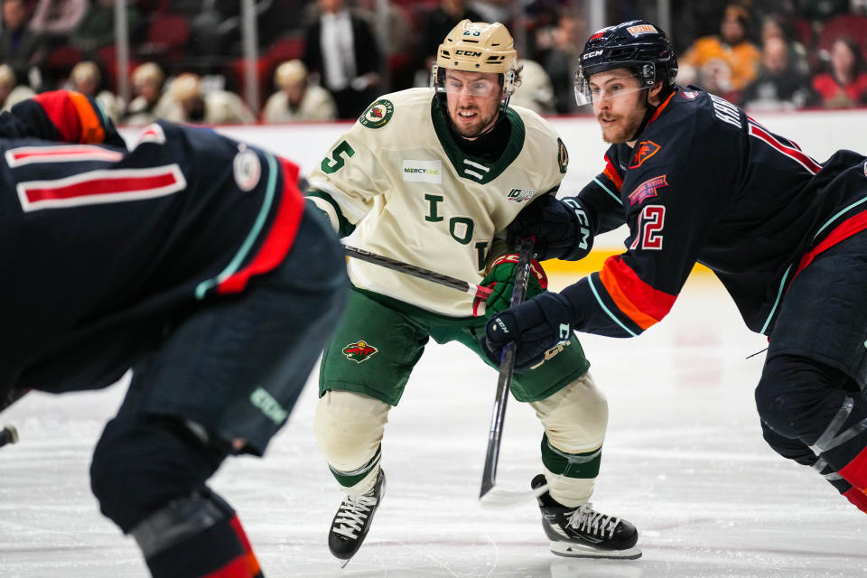 Iowa Wild forward Sammy Walker (25) battles with left wing Tye Kartye (12) during a game against the Coachella Valley Firebirds in Jan. 2023.