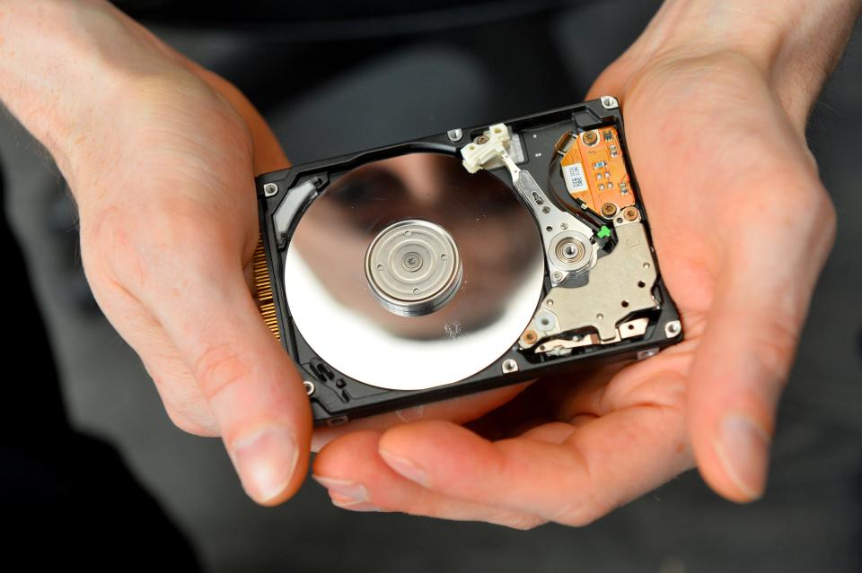 A close-up of an open hard drive being held in two hands.