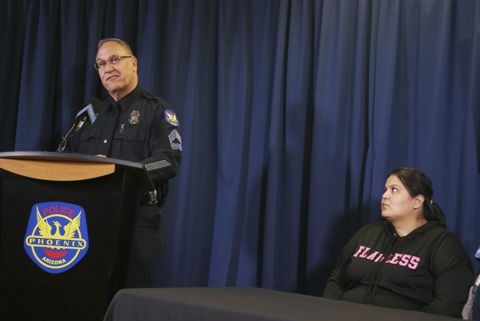 Phoenix Police Sgt. Tommy Thompson, left, talks as Shannon Vivar, 27, right, waits to speak about being in a vehicle struck by a red light runner, during a news conference at Phoenix Police headquarters Thursday, Oct. 24, 2019, in Phoenix. Authorities say Ernesto Otanez Oveso is accused of running a red light Oct. 14 in a hit-and-run car crash that nearly struck a couple pushing a stroller across a busy Phoenix street, and remains jailed on suspicion of leaving the scene of a collision and aggravated assault along with a weapons violation, a felony warrant in a probation violation and three misdemeanor warrants. (AP Photo/Ross D. Franklin)