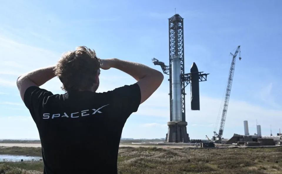 A person in a black SpaceX t-shirt looks at the Starship megarocket