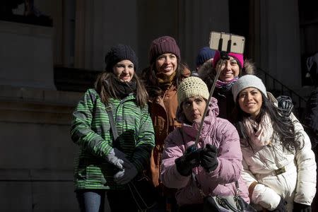 Tourists use a selfie-stick for a photograph on a cold and windy day in New York's financial district February 13, 2015 REUTERS/Brendan McDermid