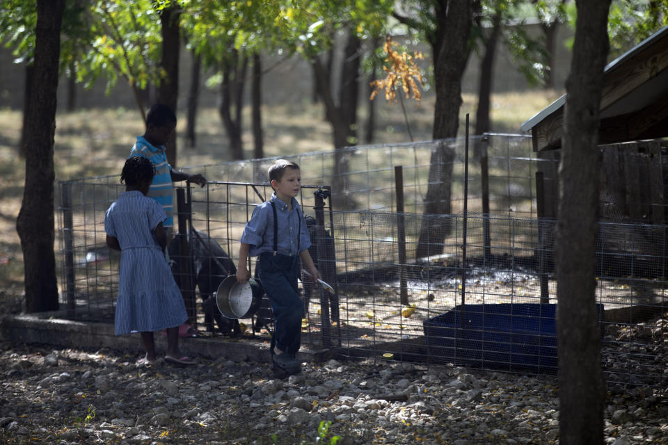 FILE - Children feed pigs at the Christian Aid Ministries headquarters in Titanyen, north of Port-au-Prince, Haiti, Monday, Nov. 22, 2021. (AP Photo/Odelyn Joseph, File)