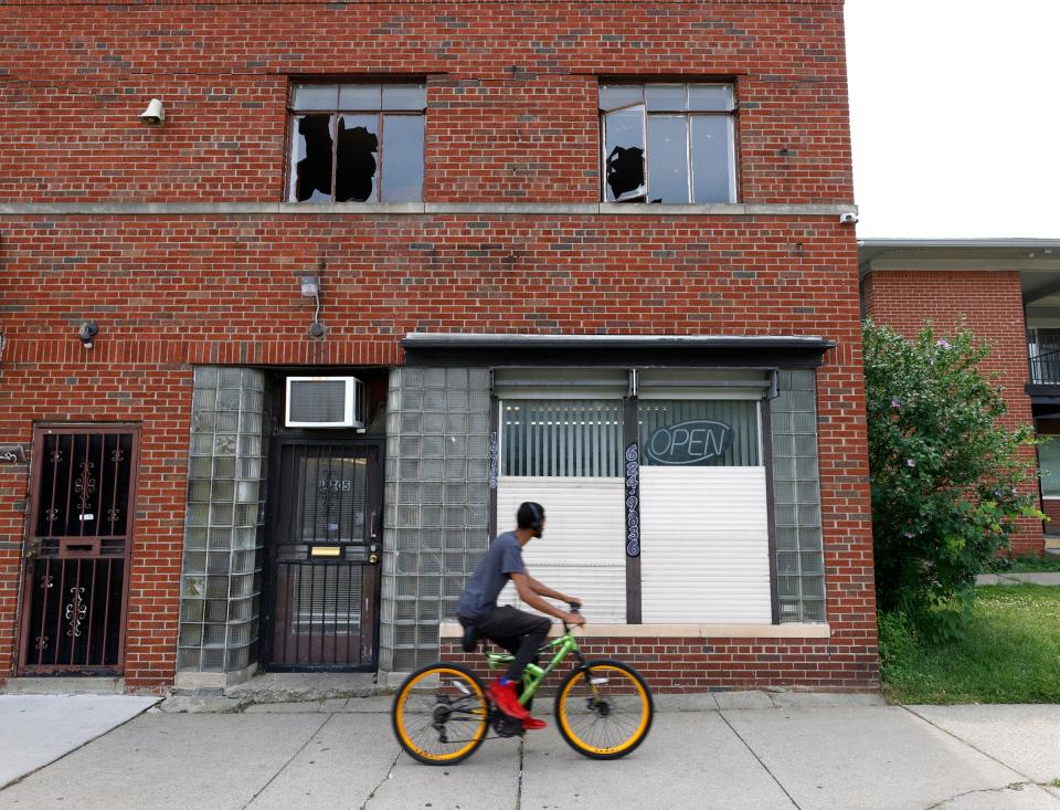 A biker passes by shot-out windows of a two-story building at Joy Road and Marlowe Street in Detroit on Thursday, July 7, 2022, where the evening before Loren Courts, a five-year veteran of the Detroit Police Department, was shot and killed by a man with an assault rifle.