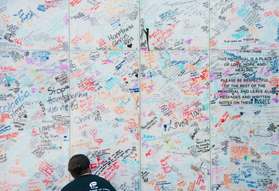 Angie Sola, a volunteer with Disney, leaves a message on the Pulse sign at the memorial. (Photo: Chris McGonigal/HuffPost)