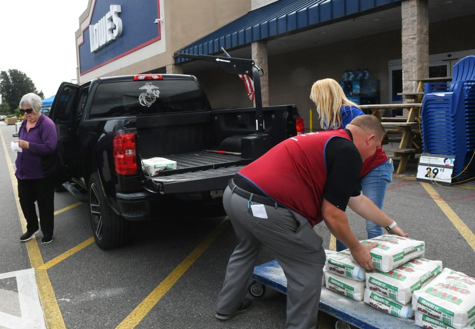 In West Melbourne, Lowe's customer Pat Alderman, at left, waits while Store Manager Thomas Wiese and Assistant Store Manager Heather Fox load bags of sand into her truck ahead of Tropical Storm Ian's potential impacts.