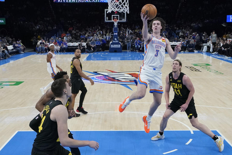 Oklahoma City Thunder guard Josh Giddey (3) goes to the basket between Utah Jazz center Walker Kessler (24) and Kelly Olynyk (41) in the second half of an NBA basketball game Sunday, March 5, 2023, in Oklahoma City. (AP Photo/Sue Ogrocki)