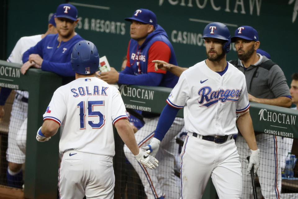 Texas Rangers' Nick Solak (15) is congratulated by Eli White, right, after he scored against the Houston Astros during the second inning of a baseball game Monday, April 25, 2022, in Arlington, Texas. (AP Photo/Michael Ainsworth)