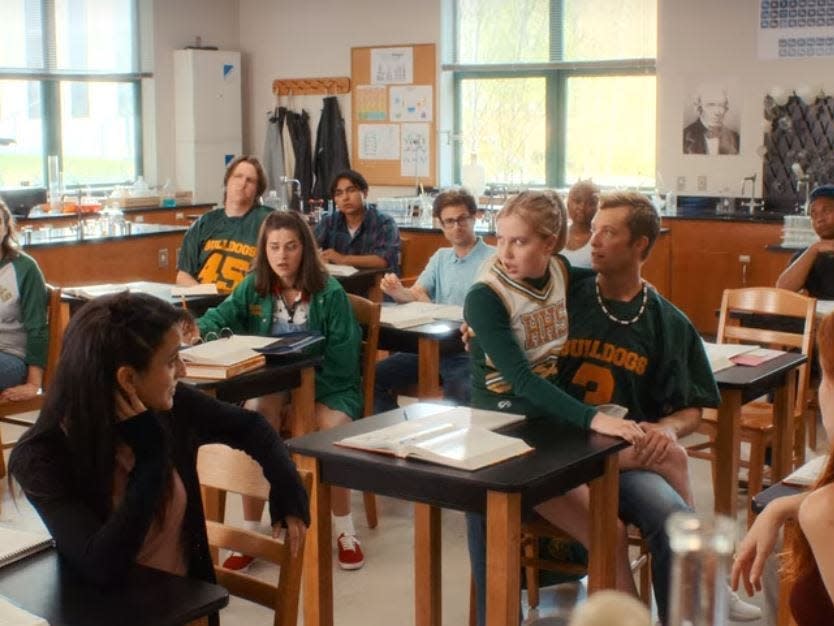 classroom ful of students in senior year including stephanie sitting on blaine's lap