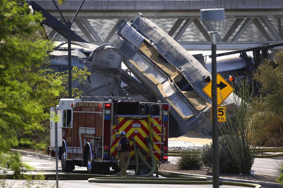 A derailed freight train hangs on a collapsed bridge onto Rio Salado Parkway Wednesday, July 29, 2020, in Tempe, Ariz. Officials say a freight train traveling on the bridge that spans a lake in the Phoenix suburb has derailed, setting the bridge ablaze and partially collapsing the structure. (AP Photo/Ross D. Franklin)