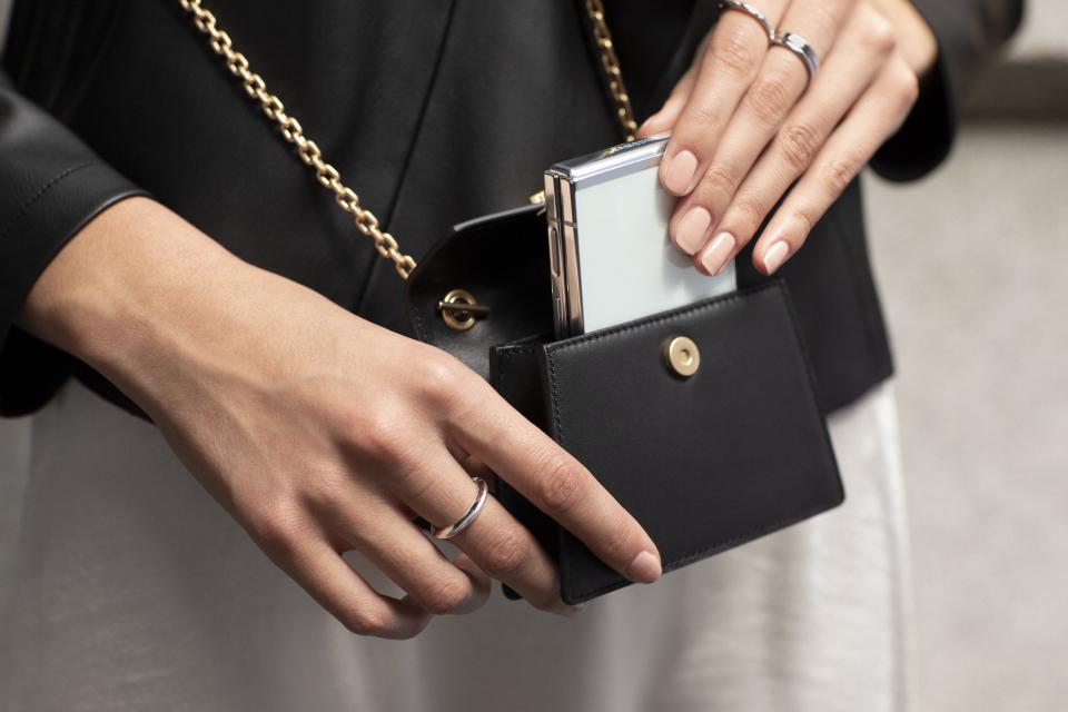 A person puts the Z Flip 5 foldable phone into a small black purse.