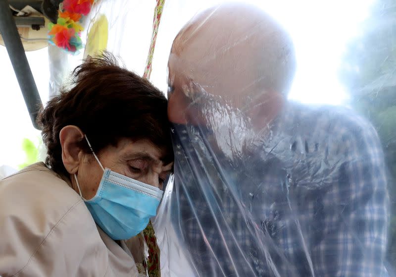 Residents at Belgian nursing home "Le Jardin de Picardie" enjoy hugs and cuddle through a wall made with plastic sheets to protect against potential COVID-19 infection in Peruwelz