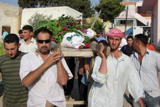 Foto distribuida por la opositoria siria Shaam News Network el 27 de julio de 2012 muestra a hombres sirios cargando el cuerpo de una víctima durante su funeral en Qusayr, a 15 km de Homs (centro). (AFP/SHAAM NEWS NETWORK | -)