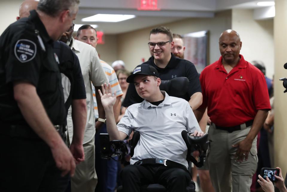Officer Nick Wilt waved at supporters while being given a push in a wheelchair by his twin brother Zack Wilt as he was released to go home from the Frazier Rehabilitation Institute in Louisville, Ky. on July 28, 2023.  Wilt was wounded while responding to the Old National Bank mass shooting in April and has been receiving care from U of L Health ever since.
