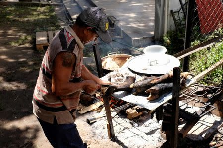 A man cooks cow feet in the backyard of a house occupied by the Apacuana commune in Caracas, Venezuela November 13, 2018. Picture taken November 13, 2018. REUTERS/Marco Bello