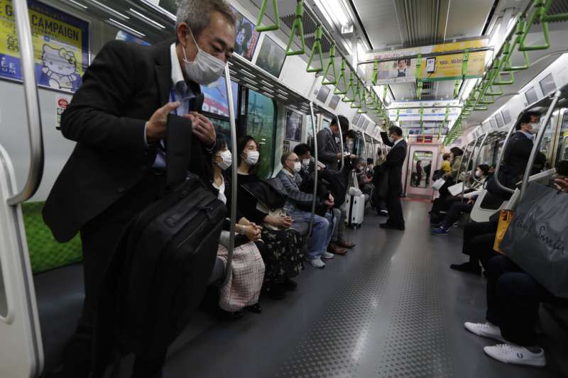 日本新冠疫情進入11月之後急遽升高，東京地鐵乘客也都戴著口罩防疫。（美聯社）