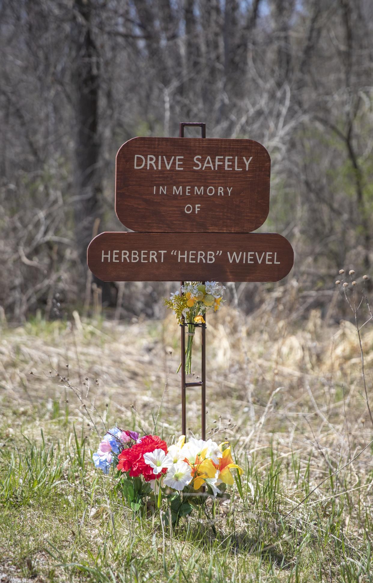 On a tight curve of West River Drive, near Portage County HH, in Stevens Point,  stands a memorial to Herbert Wievel, a 63-year-old Stevens Point man who died in early March 2024, after being hit by a driver who left the scene. Neighbors placed the memorial as well as other signs urging people to drive safely in honor of Wievel.