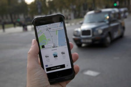 FILE PHOTO: A photo illustration shows the Uber app on a mobile telephone, as it is held up for a posed photograph, with a London Taxi in the background, in London, Britain November 10, 2017.  REUTERS/Simon Dawson/File Photo