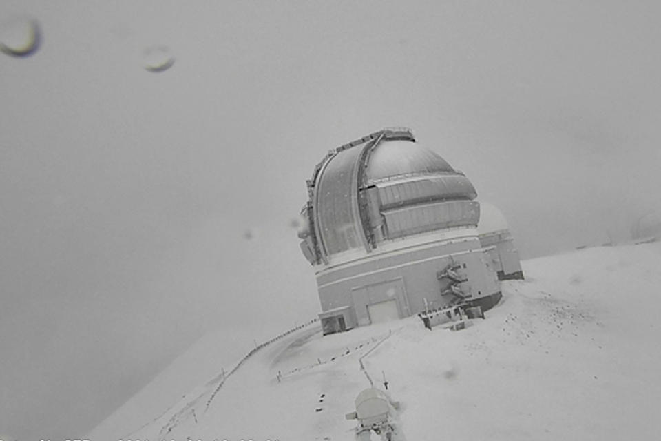 In this webcam image provided by the Canada-France-Hawaiʻi Telescope, snow is seen atop the summit of Mauna Kea in Hawaii on Monday, Dec. 6, 2021. A strong storm packing high winds and extremely heavy rain flooded roads and downed power lines and tree branches across Hawaii. (Canada-France-Hawaiʻi Telescope via AP)