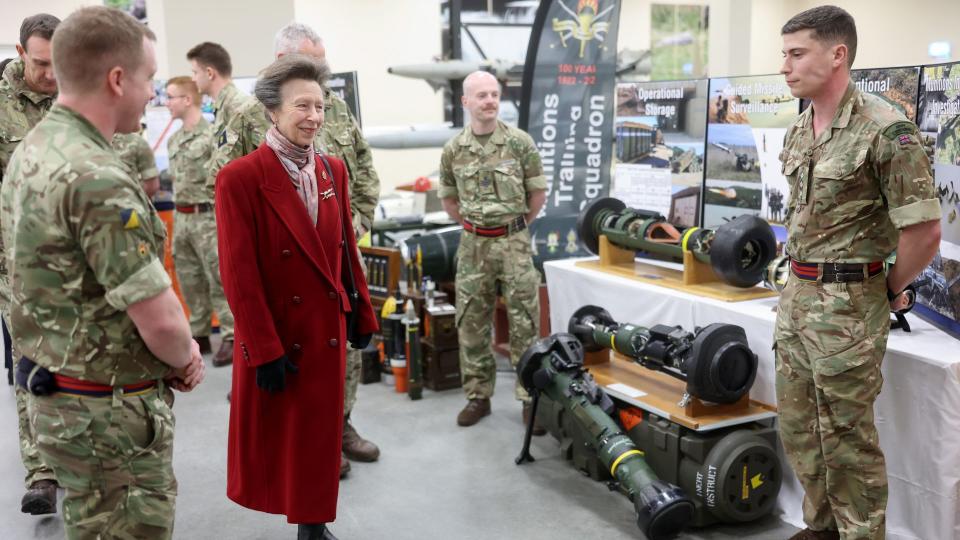 Princess Anne looking at weapons with military personnel
