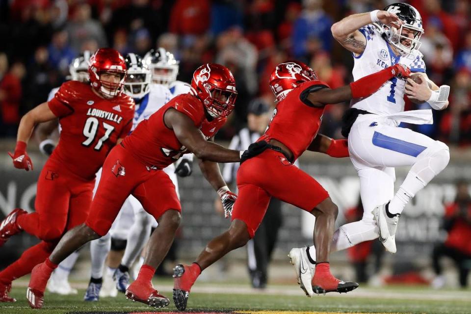 Kentucky quarterback Will Levis (7) picked up some extra yards past Louisville defenders Ashton Gillotte (97), Yasir Abdullah, center, and Chandler Jones during Saturday’s game at Cardinal Stadium.