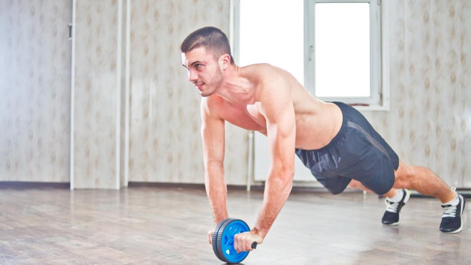 Man using an ab wheel during ab rollouts in a studio