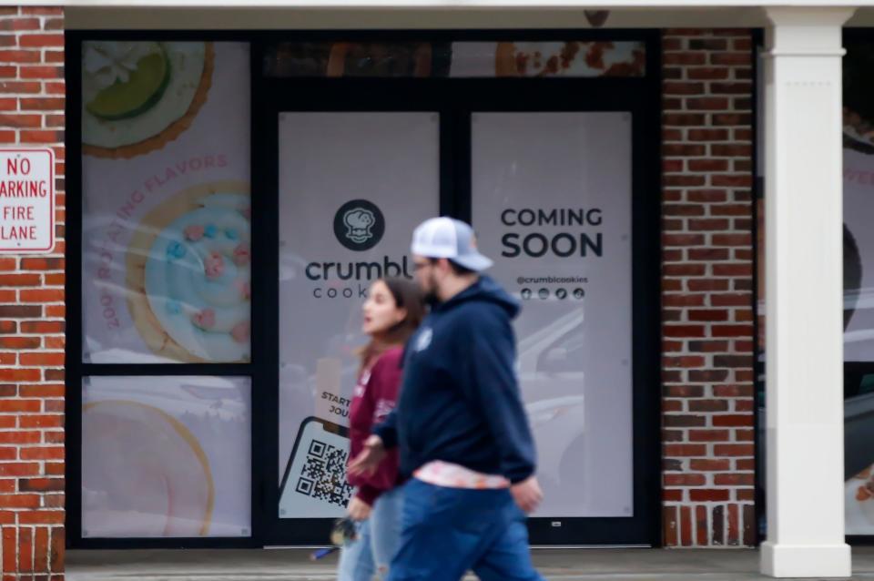 A couple walk past the entrance of the soon to open Crumbl Cookies opening next to TJ Maxx in Dartmouth.