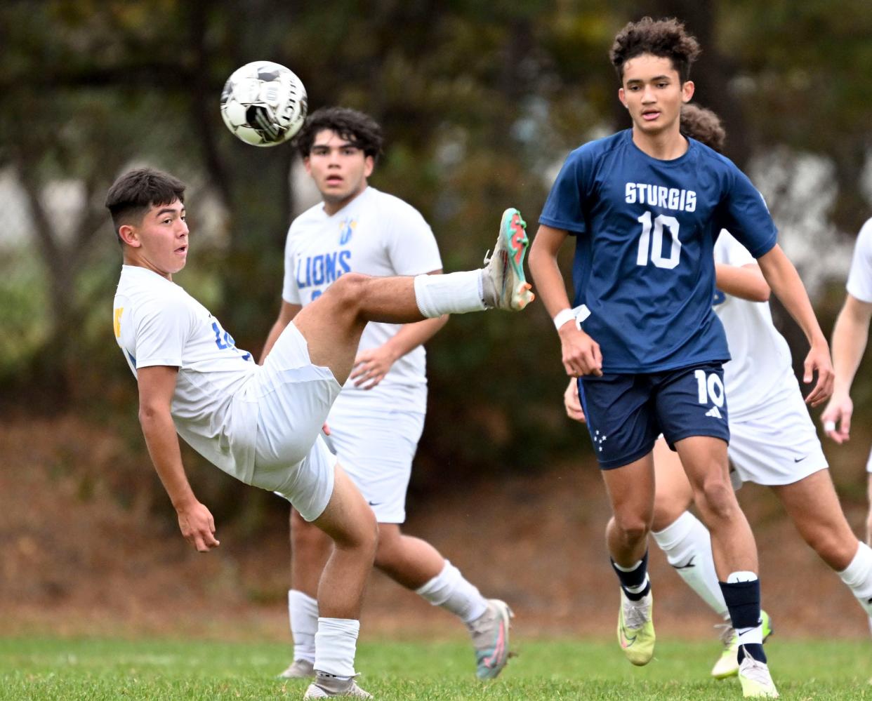 Jose Aguilar of St. John Paul II kicks the ball falling back against Pedro Melo of Sturgis East.