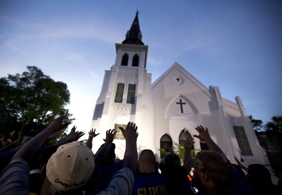 FILE - In this Friday, June 19, 2015, file photo, the men of Omega Psi Phi Fraternity Inc. lead a crowd of people in prayer outside the Emanuel AME Church, after a memorial for the nine people killed by Dylann Roof in Charleston, S.C. The funerals of Black Americans who are the victims of police brutality or white supremacist violence serve both as outlets for private mourning and as venues to air shared grief and demand justice. (AP Photo/Stephen B. Morton, File)