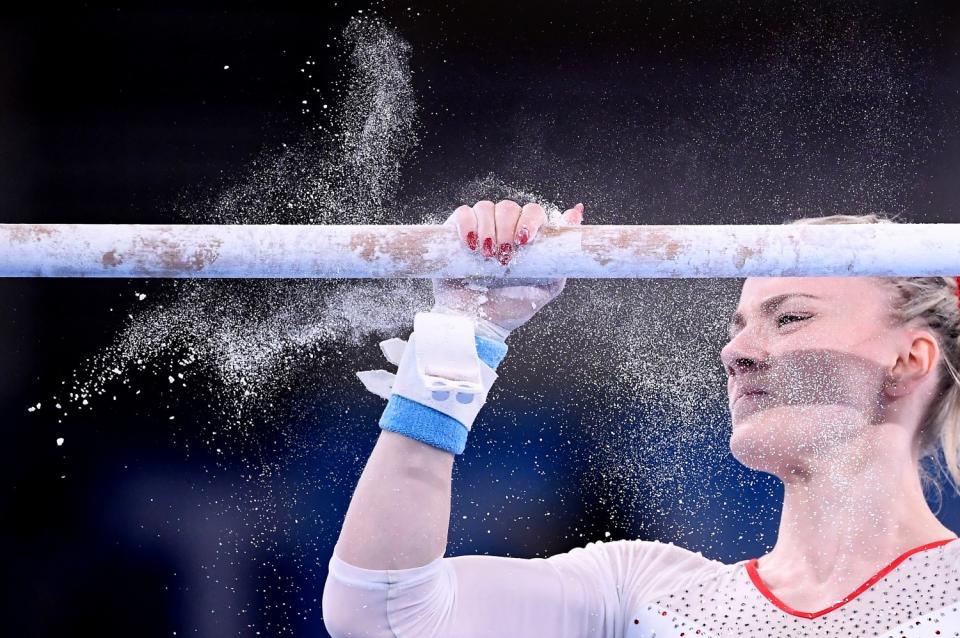 Dust flies as Gabriela Sansal rubs chalk on one of the uneven bars.