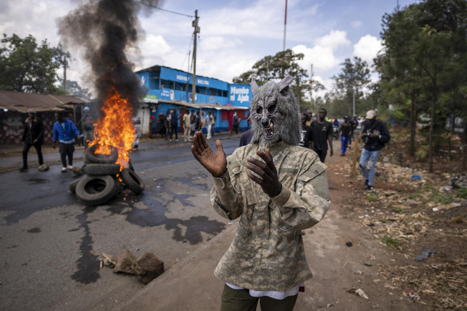 A protester wearing a wolf mask stands next to a burning barricade in the Kibera slum of Nairobi, Kenya Monday, March 20, 2023. Hundreds of opposition supporters have taken to the streets of the Kenyan capital over the result of the last election and the rising cost of living, in protests organized by the opposition demanding that the president resigns from office. (AP Photo/Ben Curtis)