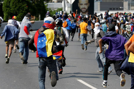 Demonstrators run away from tear gas during clashes with riot police while rallying against Venezuela's President Nicolas Maduro's government in Caracas, Venezuela April 24, 2017. REUTERS/Carlos Garcia Rawlins