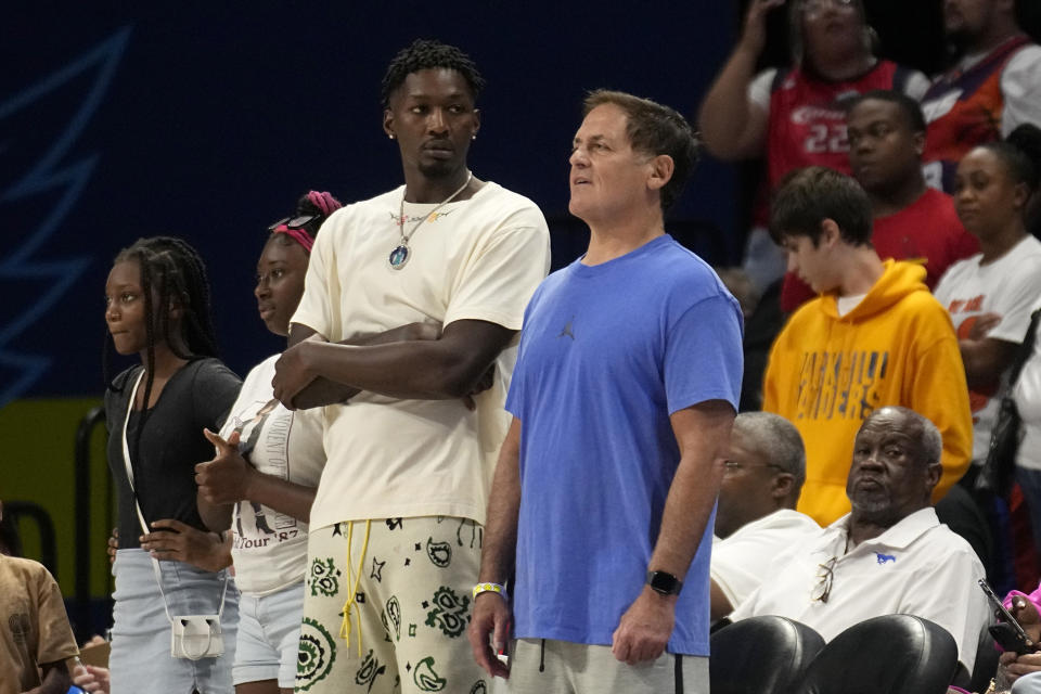 Brooklyn Nets player Dorian Finney-Smith, center left, and Dallas Mavericks team owner Mark Cuban, center right, watch play in the second half of a WNBA basketball game between the Minnesota Lynx and the Dallas Wings, Thursday, Aug. 24, 2023, in Arlington, Texas. (AP Photo/Tony Gutierrez)