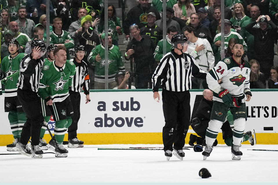 Dallas Stars' Max Domi, left, and Minnesota Wild's Matt Dumba (24) are escorted to the penalty boxes for fighting in the second period of Game 1 of an NHL hockey Stanley Cup first-round playoff series, Monday, April 17, 2023, in Dallas. (AP Photo/Tony Gutierrez)