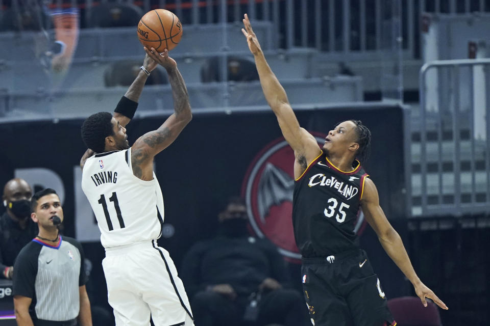 Brooklyn Nets' Kyrie Irving (11) shoots over Cleveland Cavaliers' Isaac Okoro (35) during the first half of an NBA basketball game, Wednesday, Jan. 20, 2021, in Cleveland. (AP Photo/Tony Dejak)