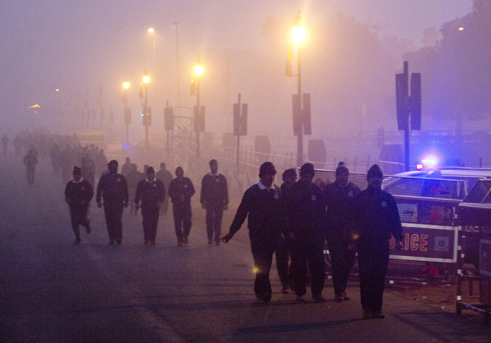 In this Wednesday, Dec. 26, 2018, photo, Indian military personals walk amidst morning smog in New Delhi, India. Authorities have ordered fire services to sprinkle water from high rise building to settle dust particles and stop burning of garbage and building activity in the Indian capital as the air quality hovered between severe and very poor this week posing a serious health hazard for millions of people. (AP Photo/Manish Swarup)