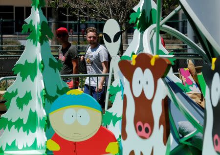 Pedestrians walk down street as workers set up a display for Comic-Con in San Diego, California United States, July 19, 2016. REUTERS/Mike Blake