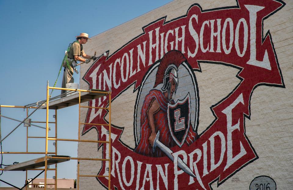 Stockton muralist Carlos Lopez applies a protective clear coat to a mural that he just completed on the music building at Lincoln High School in Stockton on Aug. 10. 2017. The mural, which was a senior gift from the class of 2016, stands 16-feet by 30-feet at the top of the southeast corner of the building and features the schools mascot, a Trojan. Lopez says it took him about 5 weeks to complete, 2 weeks longer than he normally would have, due to the uneven surface of the rough-hewn brick wall. 