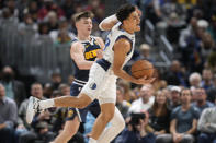 Dallas Mavericks guard Josh Green, front, reacts while driving past Denver Nuggets guard Christian Braun in the second half of an NBA basketball game Tuesday, Dec. 6, 2022, in Denver. (AP Photo/David Zalubowski)