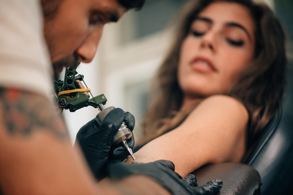 A tattoo artist working on a client