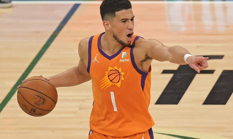 Devin Booker pointing with his left hand to direct his teammates.