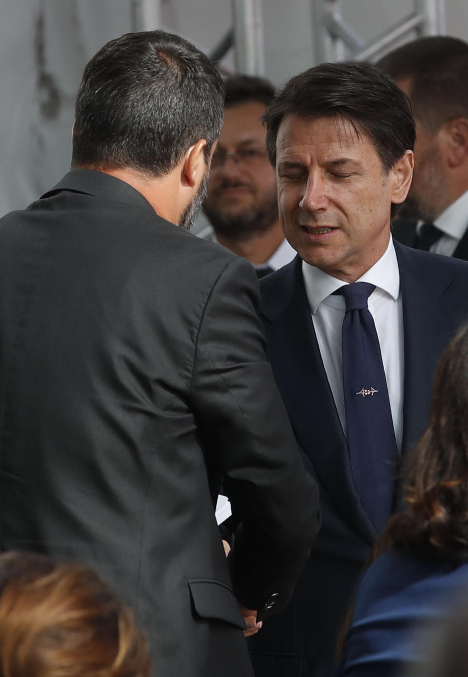 Italian Premier Giuseppe Conte shakes hands with Interior Minister Matteo Salvini as they attend a remembrance ceremony to mark the first anniversary of the Morandi bridge collapse, in Genoa, Italy, Wednesday, Aug. 14, 2019. The Morandi bridge was a road viaduct on the A10 motorway in Genoa, that collapsed one year ago killing 43 people. (AP Photo/Antonio Calanni)