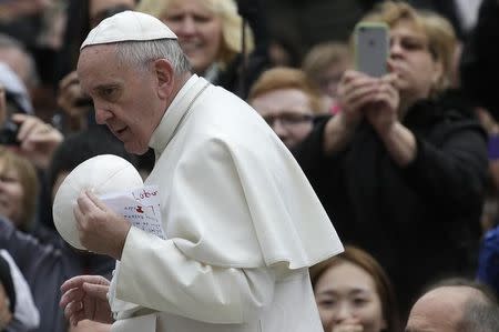 Pope Francis holds a skullcap given to him by a faithful as he arrives to lead the weekly audience in Saint Peter's Square at the Vatican February 3, 2016. REUTERS/Max Rossi