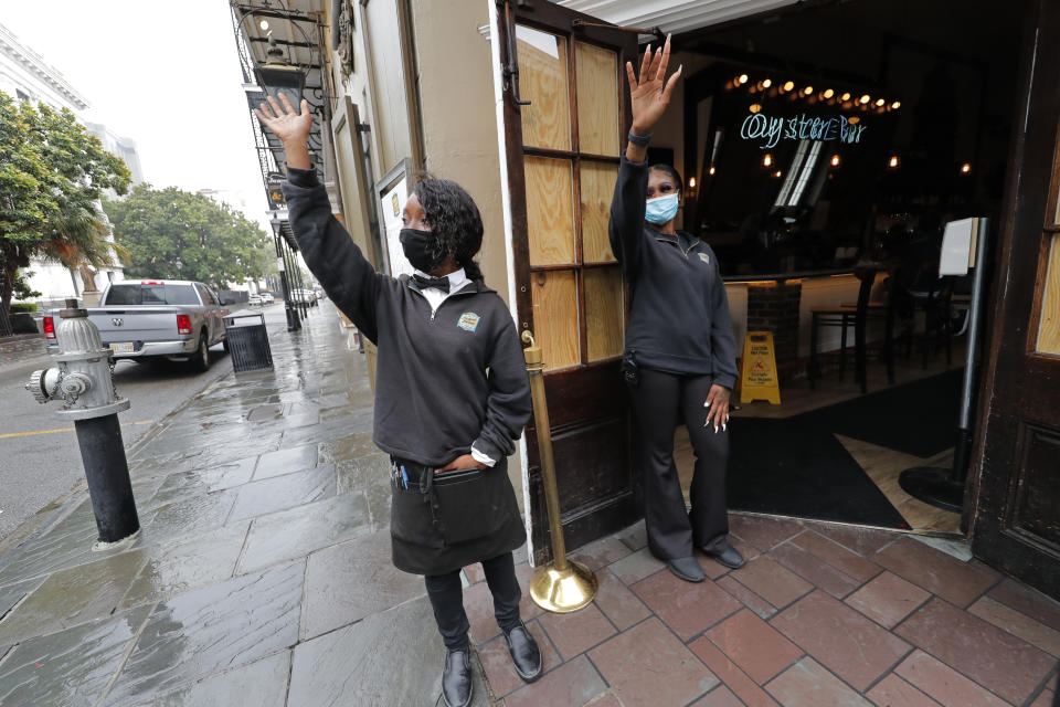Destiny Patterson, left, and Jasmine Baquet, employees of the Royal House Restaurant, try to wave down customers in the largely deserted French Quarter of New Orleans in advance of Tropical Storm Cristobal Sunday, June 7, 2020. (AP Photo/Gerald Herbert)